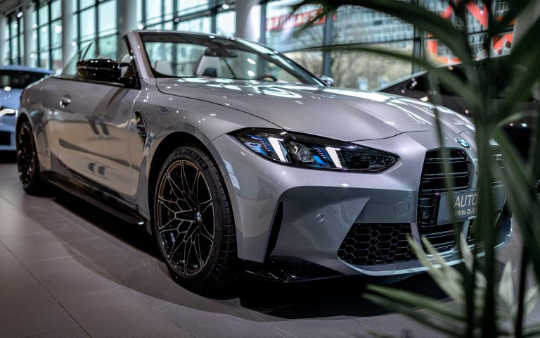 Graues BMW M4 Competition Cabrio im Autohaus, Frontansicht schräg
