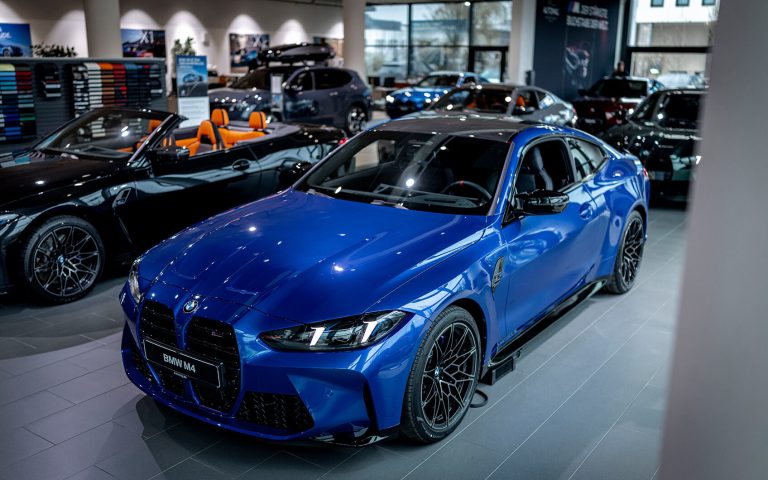 Blauer BMW M4 im Autohaus, Frontansicht von schräg oben