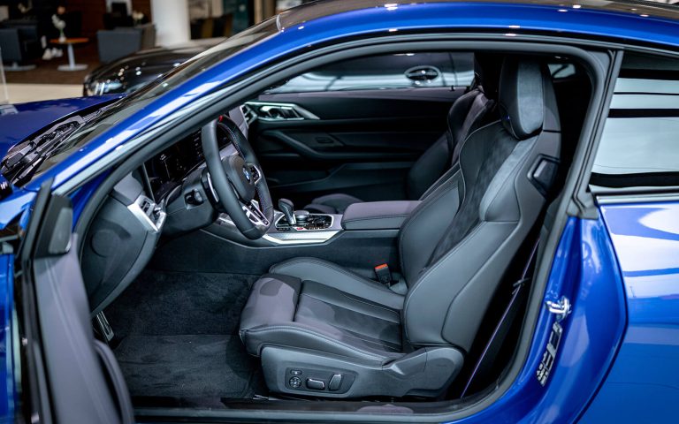 BMW M4 Innenraum mit weißen Sportsitzen und offener Fahrertür