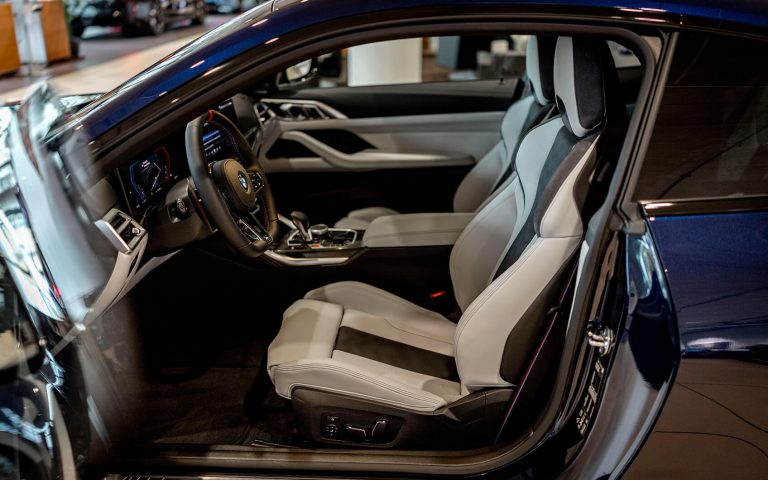 BMW M4 Innenraum mit weißen Sportsitzen und offener Fahrertür