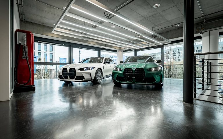 Zwei BMW M3 in Weiß und Grün im Autohaus, Frontansicht