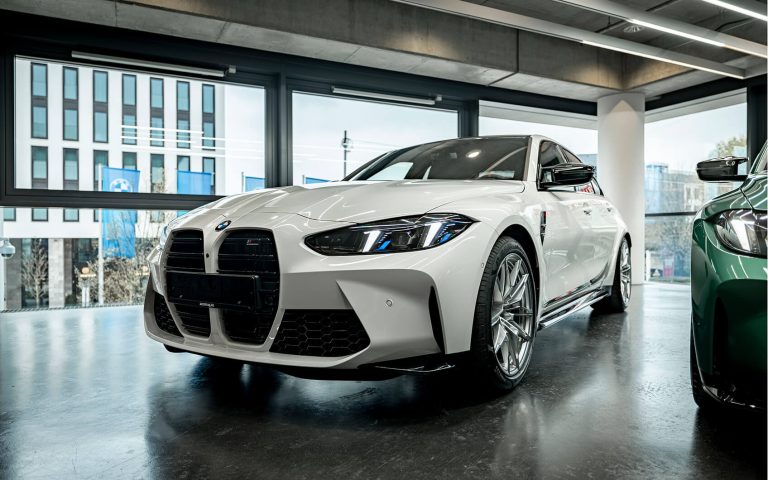 Weißer BMW M3 im Autohaus, Frontansicht schräg von links