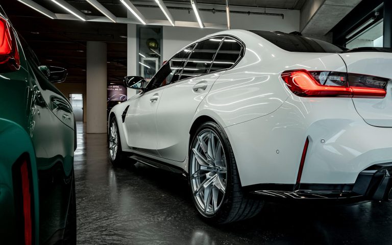 Weißer BMW M3 im Autohaus, Heckansicht schräg von links