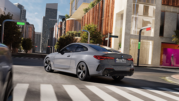 Silbergraues BMW 4er Coupé in dynamischem Design fährt auf städtischer Straße bei Sonnenschein