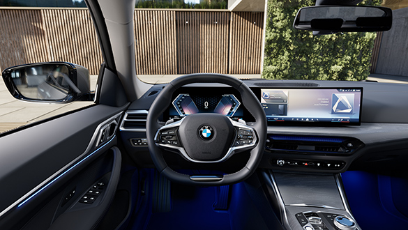 Cockpit des BMW 4er Gran Coupé aus Sicht des Fahrers mit Blick auf eine Gebäudeeinfahrt und einer mit Holz verkleideten Wand