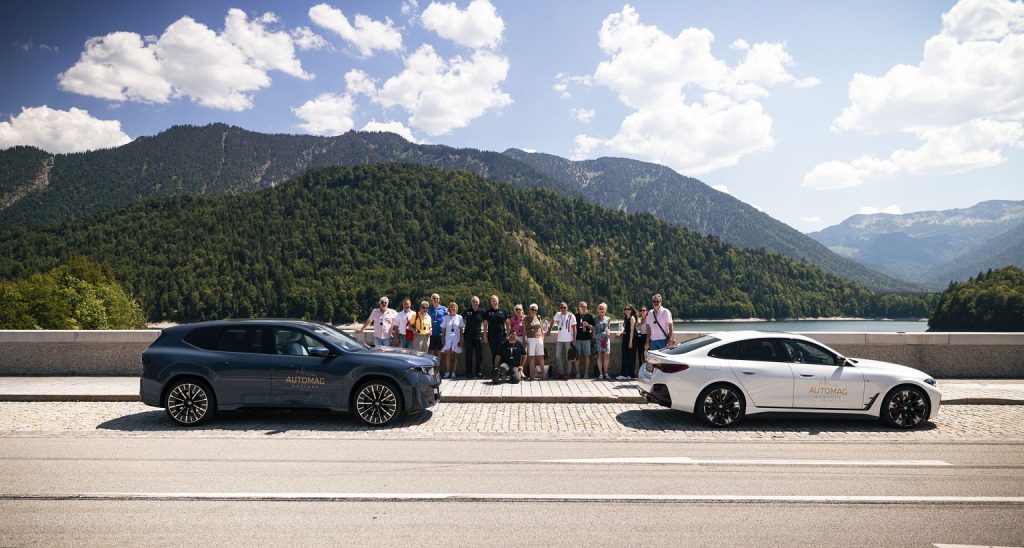 DIE AUTOMAG ALL-ELECTRIC TOUR 2026: ELEKTROMOBILITÄT HAUTNAH ERLEBT. Gruppenbild det Teilnehmer und zwei BMWs.