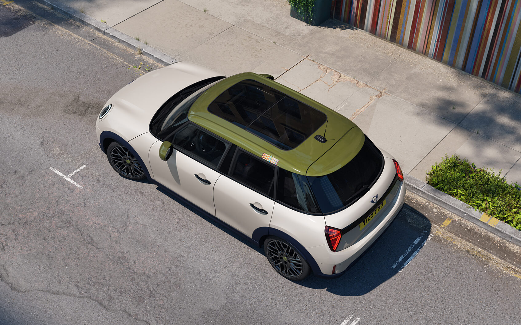 MINI 5-Türer Paul Smith Edition mit hellem Exterieur, grünem Dach und Panoramadach in einer Stadtstraße.