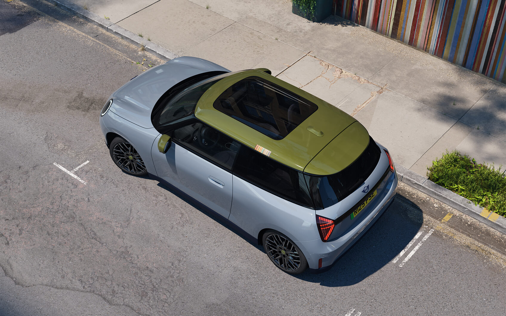 MINI Electric Paul Smith Edition mit hellem Exterieur, grünem Dach und Panoramadach in einer Stadtstraße.