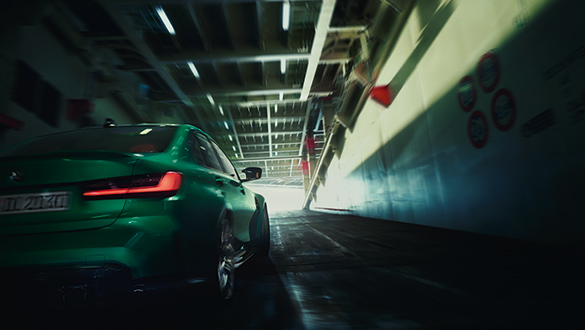 Grüne BMW M3 Limousine in Bewegung auf einem Schiff oder in einer Tiefgarage, Heckansicht.