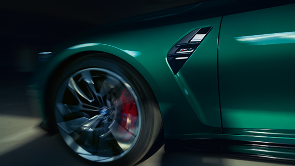 Detailaufnahme eines rotierenden Vorderrads einer grünen BMW M3 Limousine mit M-Logo.