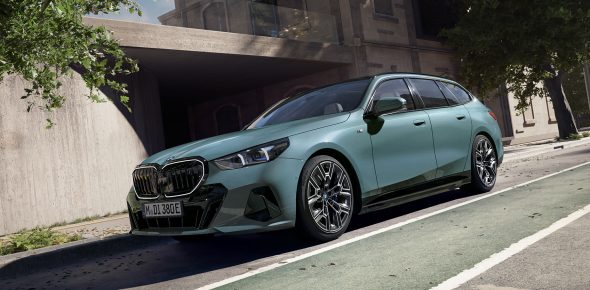 Grüner BMW i5 Touring parkt am Straßenrand, auffällige Nieren und schlanker Scheinwerfer