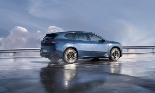 Blauer BMW iX3 in Seitenansicht auf einer Straße. Im Hintergrund ist eine freundlicher blauer Himmel mit Wolken zu sehen.