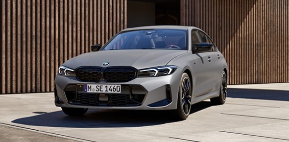 Graue BMW M340i Limousine parkt vor einem modernen urbanen Gebäude, Fokus auf Frontansicht