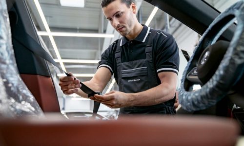 BMW-Servicemitarbeiter überprüft Sicherheitsgurt im Fahrzeuginnenraum.